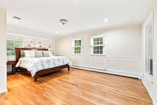 bedroom with light wood-style floors, a baseboard radiator, ornamental molding, a decorative wall, and recessed lighting
