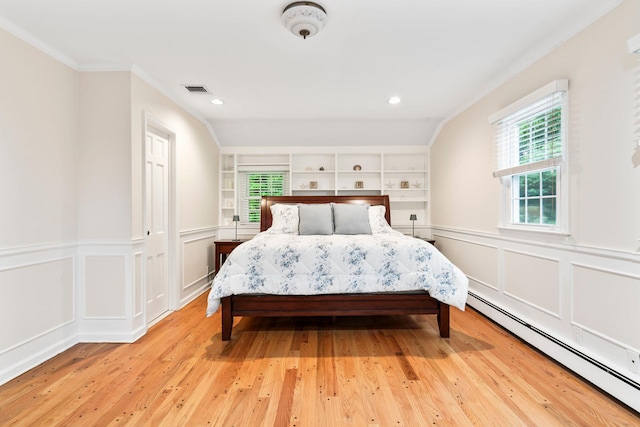 bedroom with a baseboard radiator, light wood-style flooring, ornamental molding, a decorative wall, and recessed lighting