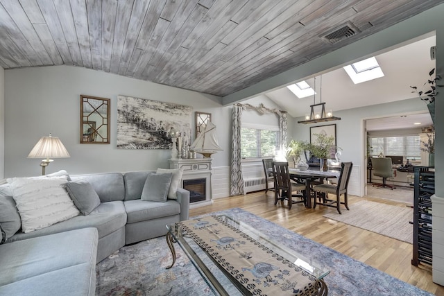 10 Falcon Pl, Huntington, NY 11743 - living area featuring vaulted ceiling, a skylight, a glass covered fireplace, radiator, and wood finished floors