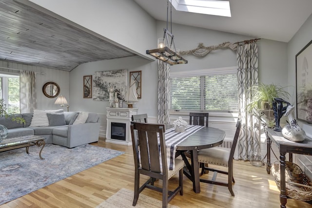 10 Falcon Pl, Huntington, NY 11743 - dining area featuring vaulted ceiling, light wood-type flooring, a skylight, and a fireplace