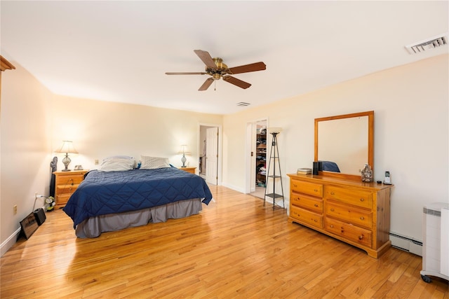 17 Stonegate Dr, Hyde Park, NY 12538 - bedroom featuring light wood-style floors, a baseboard heating unit, ceiling fan, a walk in closet, and baseboards