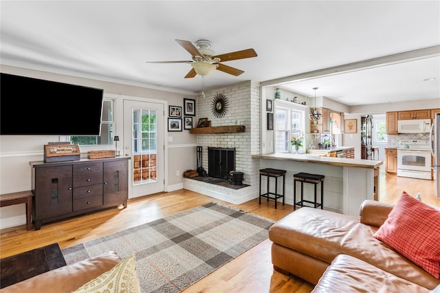85 Shore Rd, Amityville, NY 11701 - living area with light wood-type flooring, a ceiling fan, a fireplace, baseboards, and ornamental molding