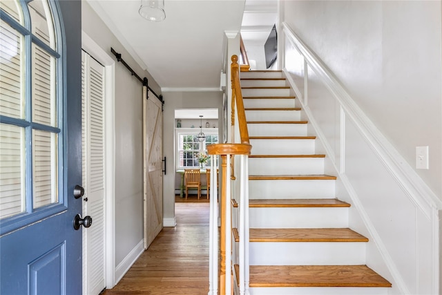 85 Shore Rd, Amityville, NY 11701 - stairway featuring a barn door, ornamental molding, wood finished floors, and a baseboard radiator