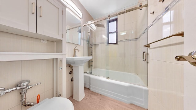 bathroom with shower / bath combination with glass door, toilet, wood finished floors, and a sink