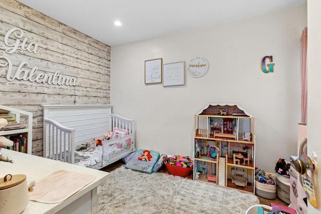 25-36 83rd St, East Elmhurst, NY 11370 - bedroom featuring wooden walls, recessed lighting, a nursery area, wood finished floors, and an accent wall
