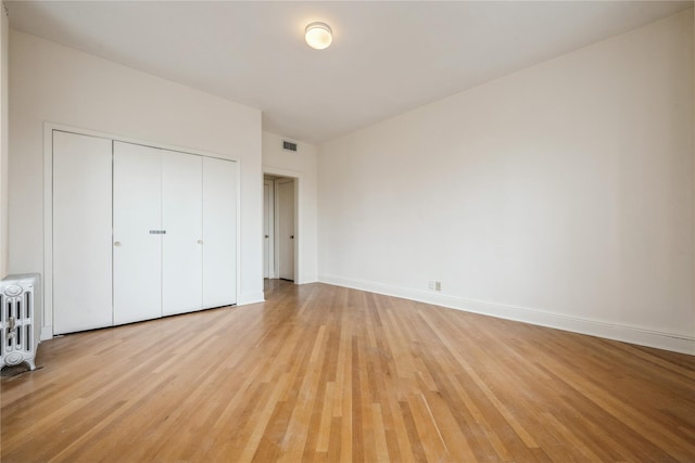 1175 E Broadway Unit 2J, Hewlett, NY 11557 - unfurnished bedroom with radiator, light wood-style floors, a closet, and baseboards