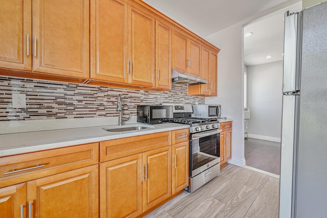 5130 35th St, Long Island City, NY 11101 - kitchen with under cabinet range hood, stainless steel appliances, a sink, light countertops, and decorative backsplash