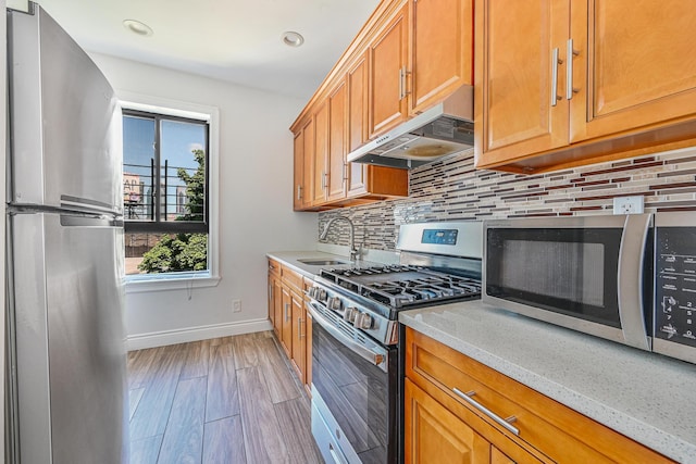 5130 35th St, Long Island City, NY 11101 - kitchen featuring appliances with stainless steel finishes, under cabinet range hood, tasteful backsplash, baseboards, and light stone countertops