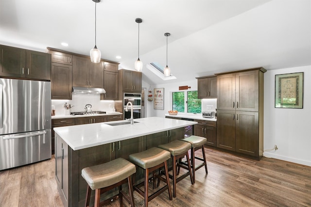 42 Raspberry Ln, Carmel, NY 10512 - kitchen featuring stainless steel appliances, a sink, under cabinet range hood, dark brown cabinets, and a kitchen bar