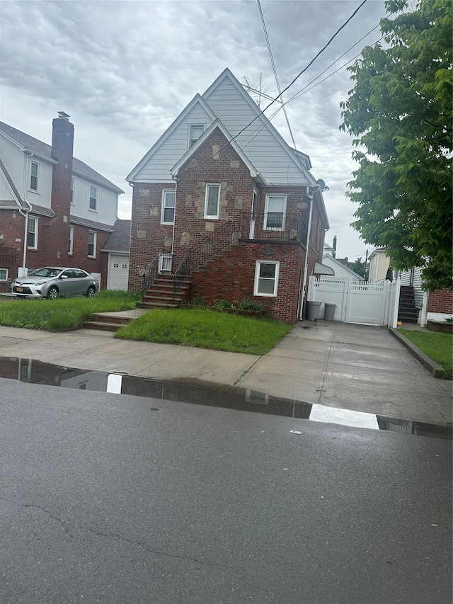 view of front of property with brick siding, fence, and a gate