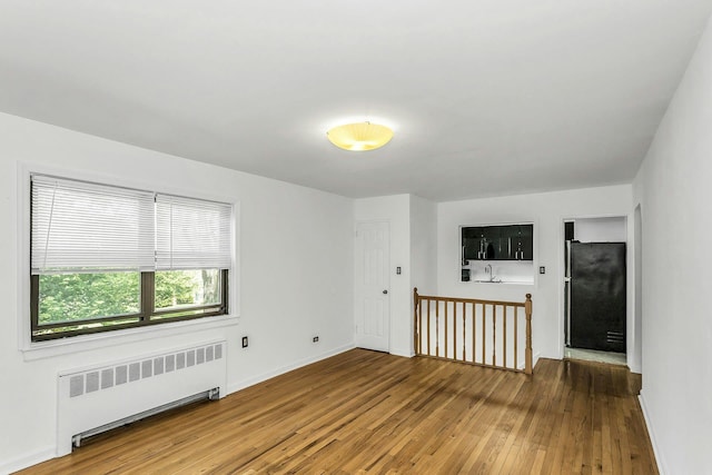 219-36 75th Ave Unit 243A2, Bayside, NY 11364 - empty room with radiator heating unit, wood-type flooring, and baseboards