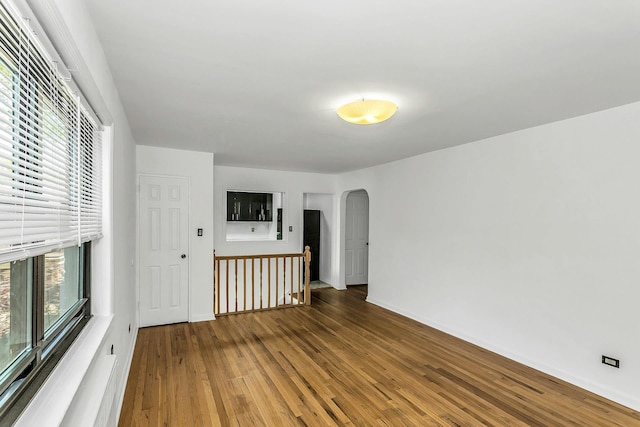 219-36 75th Ave Unit 243A2, Bayside, NY 11364 - unfurnished living room with arched walkways, plenty of natural light, wood finished floors, and baseboards