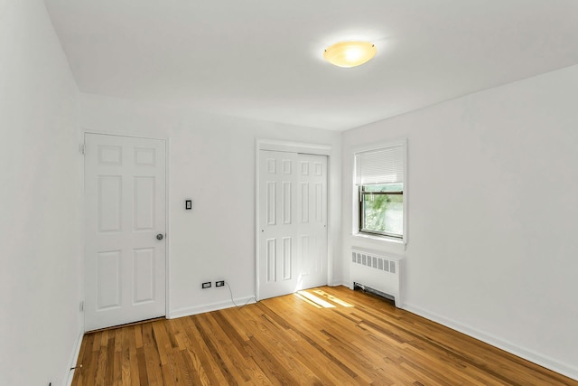 219-36 75th Ave Unit 243A2, Bayside, NY 11364 - unfurnished bedroom featuring radiator, wood finished floors, baseboards, and a closet