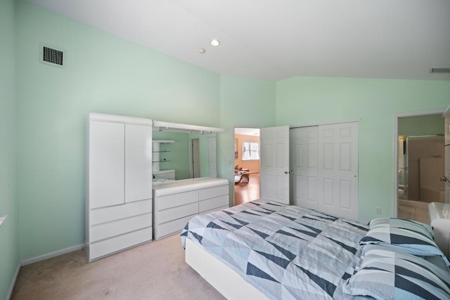 bedroom with light colored carpet, a closet, connected bathroom, baseboards, and high vaulted ceiling