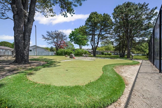 view of yard featuring an area to practice putting and fence