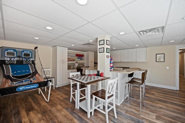 dining area featuring dark wood-style flooring, baseboards, a paneled ceiling, and recessed lighting