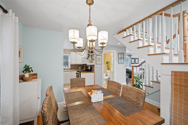 49 Oregon St, Long Beach, NY 11561 - dining space with a chandelier, stairs, light wood finished floors, and baseboards