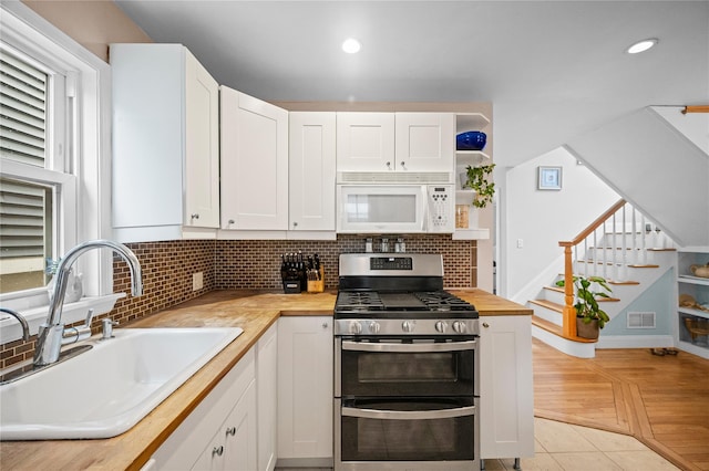 49 Oregon St, Long Beach, NY 11561 - kitchen featuring white microwave, range with two ovens, a sink, butcher block countertops, and backsplash