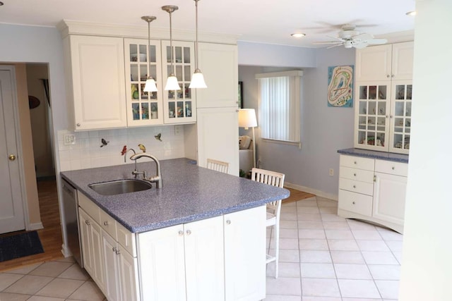 kitchen featuring a sink, a ceiling fan, glass insert cabinets, tasteful backsplash, and light tile patterned floors