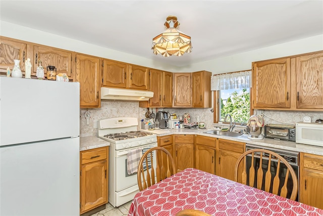 kitchen featuring white appliances, under cabinet range hood, a sink, and light countertops