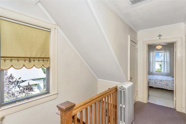 corridor featuring dark carpet, an upstairs landing, radiator, and ornamental molding