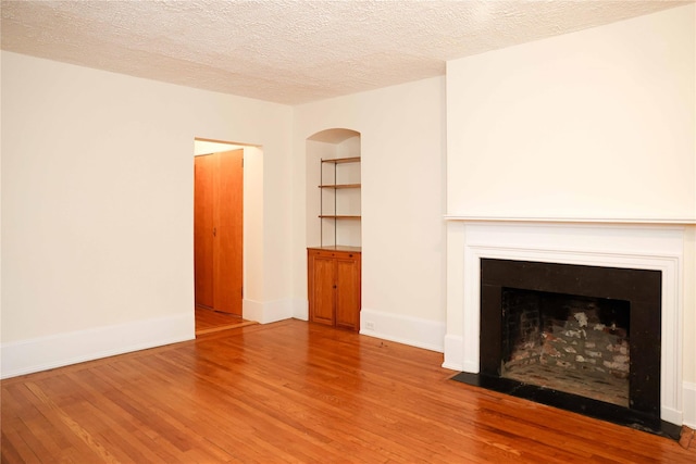 808 Bronx River Rd Unit 1A, Yonkers, NY 10708 - unfurnished living room with wood finished floors, a fireplace with flush hearth, a textured ceiling, and baseboards