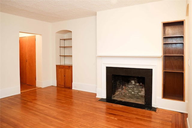 808 Bronx River Rd Unit 1A, Yonkers, NY 10708 - unfurnished living room with wood finished floors, a fireplace with flush hearth, a textured ceiling, and baseboards