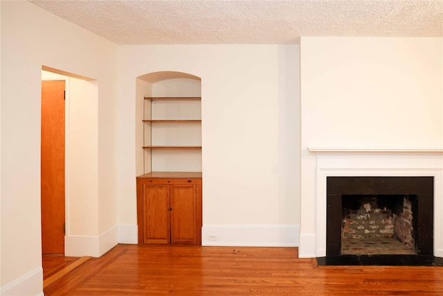 808 Bronx River Rd Unit 1A, Yonkers, NY 10708 - unfurnished living room featuring light wood-style floors, a textured ceiling, and a fireplace with flush hearth