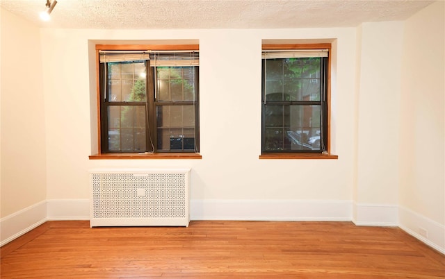 808 Bronx River Rd Unit 1A, Yonkers, NY 10708 - unfurnished room with wood finished floors, radiator heating unit, baseboards, healthy amount of natural light, and a textured ceiling