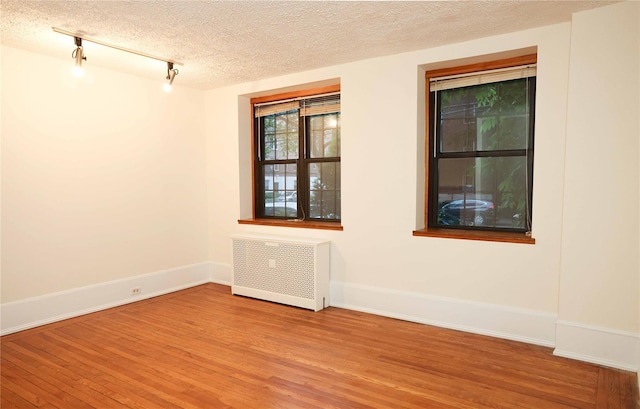 808 Bronx River Rd Unit 1A, Yonkers, NY 10708 - empty room with radiator, wood finished floors, track lighting, baseboards, and a textured ceiling