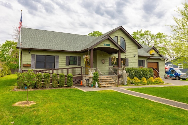 view of front of property featuring a shingled roof, a front yard, covered porch, asphalt driveway, and an attached garage