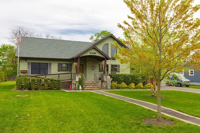 view of front of house with covered porch, a front lawn, and roof with shingles