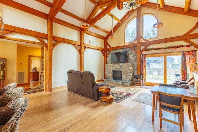 living area featuring high vaulted ceiling, a stone fireplace, beam ceiling, and wood-type flooring