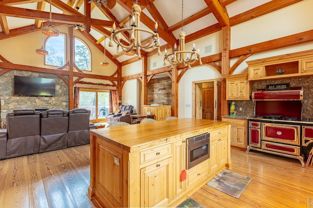 kitchen with a chandelier, high vaulted ceiling, appliances with stainless steel finishes, wooden counters, and light wood finished floors