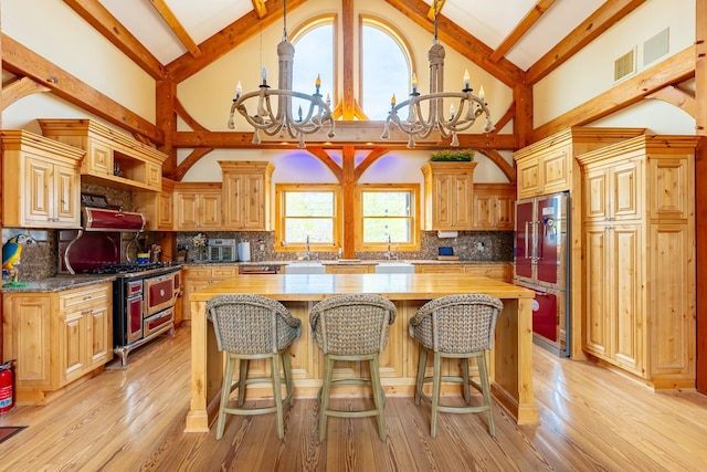 kitchen with high vaulted ceiling, a chandelier, gas stove, refrigerator, and a center island