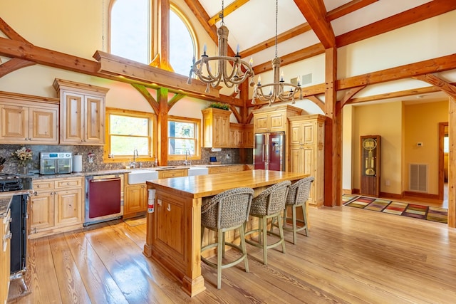 kitchen with dishwashing machine, high vaulted ceiling, a chandelier, stainless steel fridge, and butcher block counters