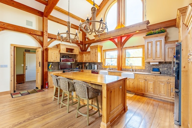 kitchen featuring a sink, butcher block counters, high vaulted ceiling, a chandelier, and decorative backsplash