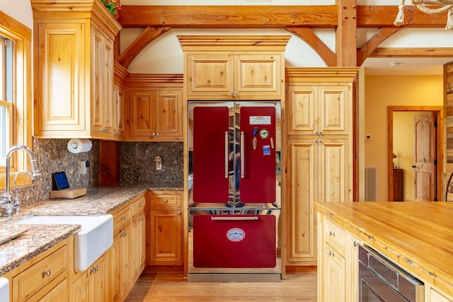kitchen with refrigerator, a sink, tasteful backsplash, light wood finished floors, and light stone countertops