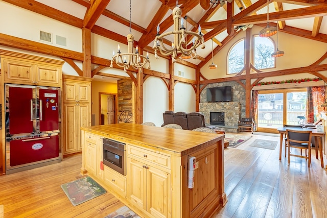 kitchen with high end refrigerator, butcher block countertops, high vaulted ceiling, stainless steel microwave, and a chandelier