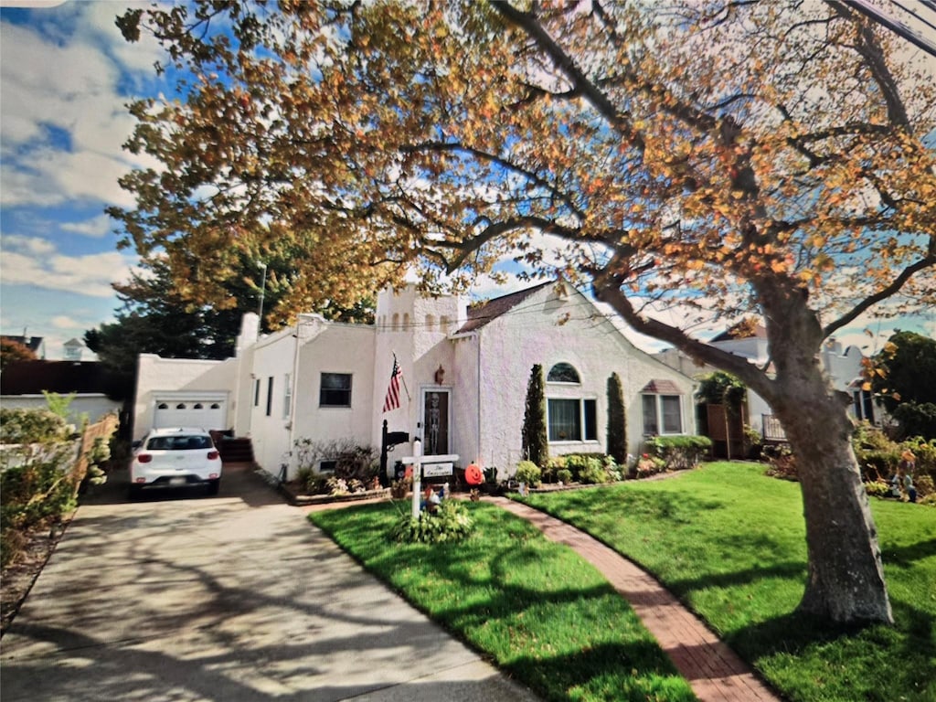 12 Bay Front Dr, Baldwin, NY 11510 - mediterranean / spanish-style house with driveway, a front lawn, a garage, and stucco siding