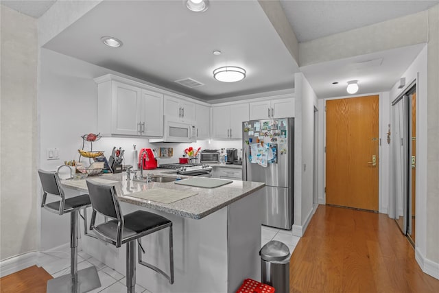 50 E Hartsdale Ave Unit 3S, Hartsdale, NY 10530 - kitchen featuring freestanding refrigerator, white microwave, a sink, a peninsula, and white cabinetry