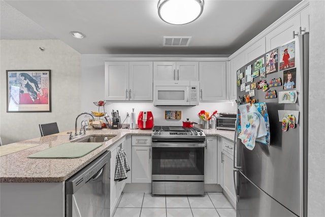 50 E Hartsdale Ave Unit 3S, Hartsdale, NY 10530 - kitchen with appliances with stainless steel finishes, a sink, a peninsula, light tile patterned flooring, and white cabinetry