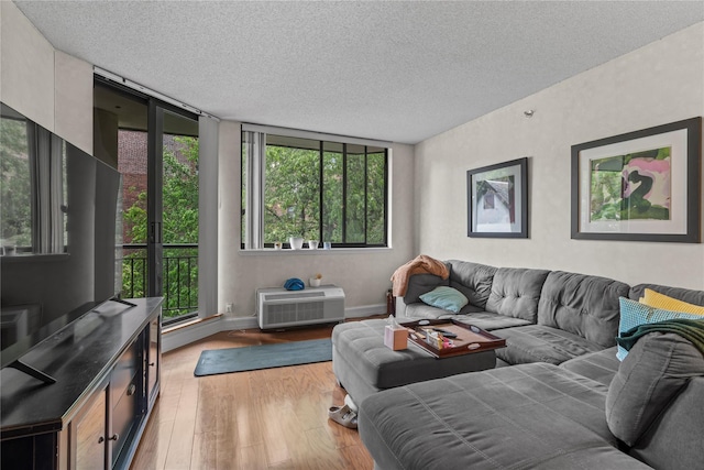 50 E Hartsdale Ave Unit 3S, Hartsdale, NY 10530 - living area with light wood-style floors, a textured ceiling, baseboards, and a wall mounted air conditioner
