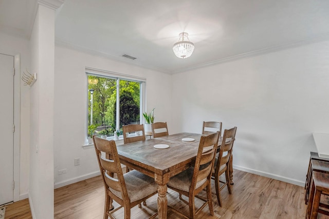 dining area featuring ornamental molding, light wood-style floors, and baseboards
