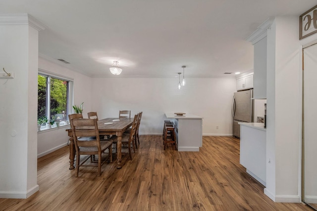 dining area with baseboards, crown molding, and wood finished floors