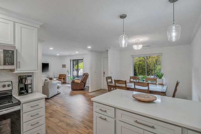 kitchen with appliances with stainless steel finishes, open floor plan, light countertops, light wood finished floors, and hanging light fixtures