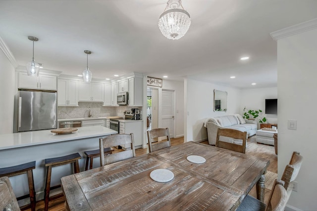 dining area featuring a chandelier, recessed lighting, wood finished floors, crown molding, and baseboards