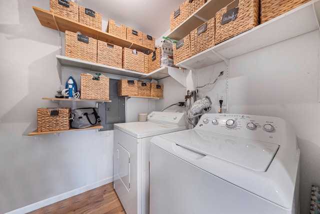 clothes washing area featuring washer and dryer, wood finished floors, and baseboards