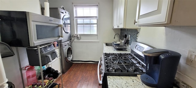 138-10 77th Ave Unit 60E, Kew Garden Hills, NY 11367 - kitchen with stacked washer and clothes dryer, light countertops, a sink, stainless steel range with gas cooktop, and dark wood-style floors