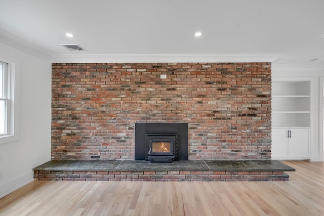 3 Thomas Dr, Wading River, NY 11792 - detailed view of wood finished floors, a wood stove, baseboards, crown molding, and built in shelves